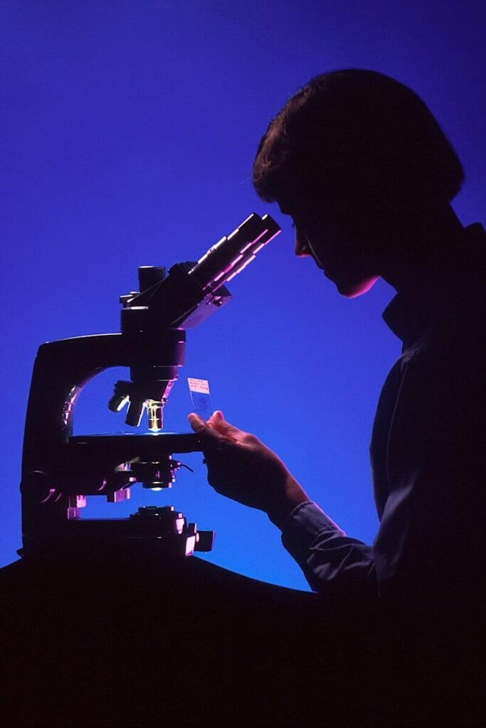 silhouette of person using microscope